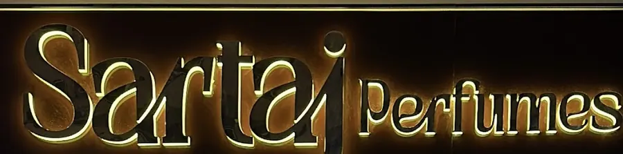 The lit Sartaj Perfumes sign over the shop